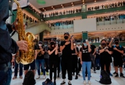 Protesters wearing masks in defiance of a recently imposed ban on face coverings perform at a shopping mall in Hong Kong, Oct.13, 2019.