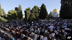 Palestinians pray in front of the Dome of the Rock shrine in Jerusalem, June 15, 2018 during the traditional morning prayer of the Muslim holiday of Eid al-Fitr.