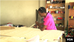 Lilian Wairimu cuts the material needed for the beanbag. The material is cut into eight pieces with inner and outer lining, then is stitched together with a zipper to hold the foam perfectly. (M. Yusuf/VOA)
