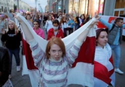 A woman carries a historical white-red-white flag of Belarus during an opposition demonstration against presidential election results in Minsk, Belarus, Aug. 28, 2020.