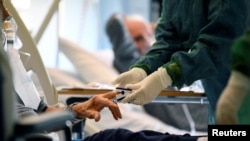 Medical staff in a protective suit treats a patient suffering from coronavirus disease (COVID-19) in an intensive care unit at the Oglio Po hospital in Cremona, Italy, March 19, 2020.