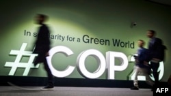 Луѓе поминуваат покрај логото на местото на Конференцијата за климатски промени на Обединетите нации 2024 година (КОП29) во Баку на 11 ноември 2024 година.