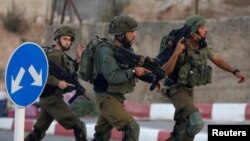 Israeli soldiers run near the scene where a Palestinian, who according to the Israeli military attempted to stab a soldier, was shot dead in Hebron in the occupied West Bank, Sept. 3, 2018.