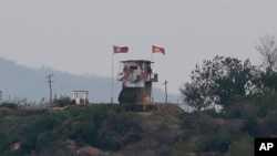 FILE - A North Korean flag (left) flutters in the wind at a military guard post in Paju, at the country's border with South Korea, May 3, 2020. 