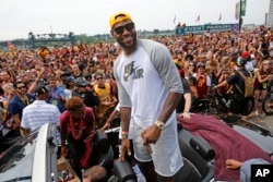 Cleveland superstar LeBron James, center, stands in the back of a Rolls Royce at the beginning of a parade in downtown Cleveland, Wedensday, June 22, 2016, celebrating the Cavaliers' NBA Championship.