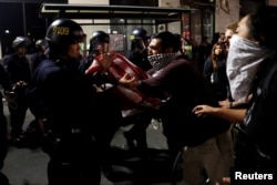 A masked demonstrator scuffles with police officers during a demonstration following the election of Donald Trump as president of the United States, in Oakland, California, Nov. 10, 2016.