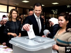 This photo released on the official Facebook page of Syrian Presidency, shows Syrian President Bashar Assad casting his ballot in the parliamentary elections, as his wife Asma, left, is standing next to him, in Damascus, Syria, Wednesday, April 13, 2016.