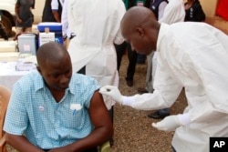 FILE - A health worker prepares to inject a man with an Ebola vaccine in Conakry, Guinea, March 7, 2015.