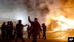 Polisi mengamankan kota Ferguson, Missouri sementara demonstran membakar sebuah gedung di sana, Senin (24/11).