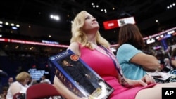 Dana Dougherty from Deltona, Fla., watches as she holds a Donald Trump figure during first day of the Republican National Convention in Cleveland, Monday, July 18, 2016. (AP Photo/Carolyn Kaster)