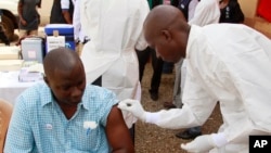 A health worker prepares to inject a man with an Ebola vaccine in Conakry, Guinea, March 7, 2015.
