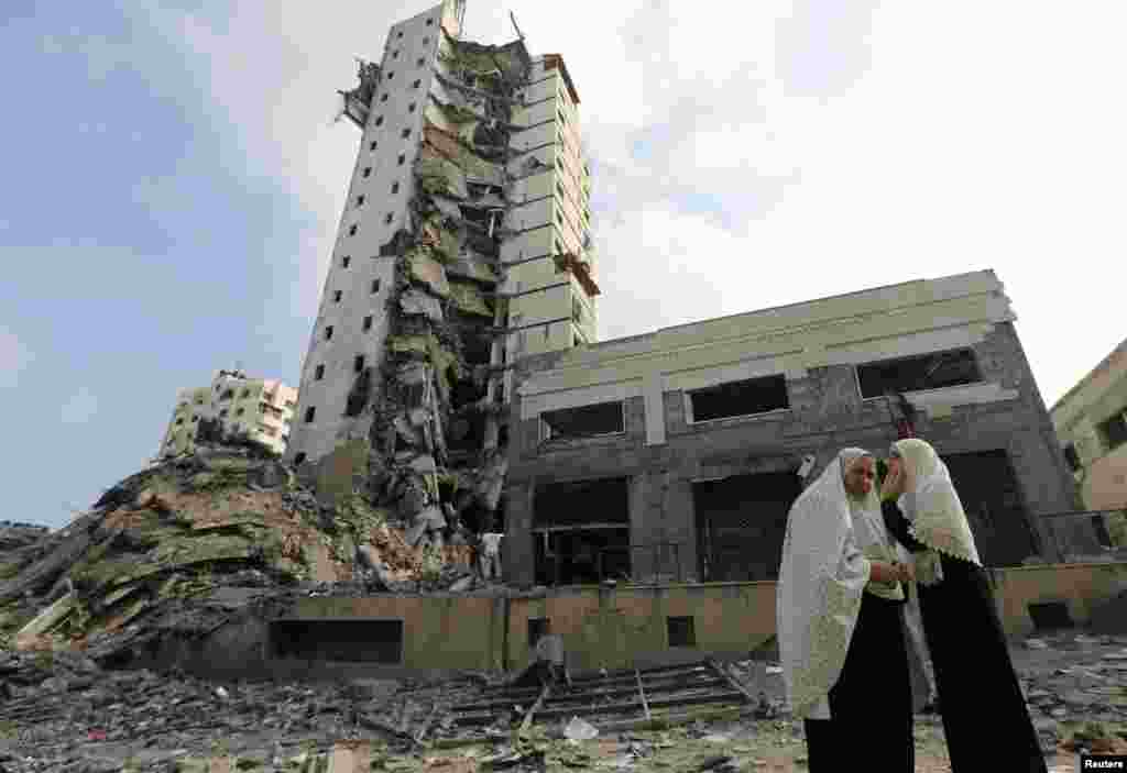 Palestinian women stand next to the remains of one of Gaza&#39;s tallest apartment towers, which was destroyed by an air strike, in Gaza City, Aug. 26, 2014.