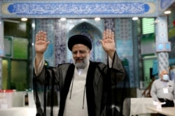 Ebrahim Raisi, a candidate in Iran's presidential elections, raises his hands as he casts his vote at a polling station in Tehran, Iran, June 18, 2021.