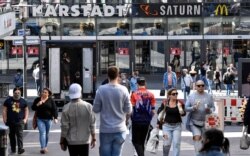 People walk to a shopping center as many smaller stores are allowed to open in Essen, Germany, April 20, 2020. Europe's biggest economy, starts reopening some of its stores and factories after weeks of lockdown.