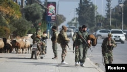 Opposition fighters walk along a street in Aleppo, Syria, after the government army said dozens of its soldiers were killed in a major attack by rebels who swept into the city on Nov. 30, 2024.