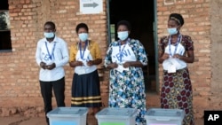 Electoral officials wearing face masks to protect against the coronavirus, stand by ballot boxes before voters cast their votes in a presidential election, in Giheta, Gitega province, Burundi, May 20, 2020. 