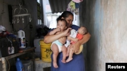 Jaqueline (L), 25, holds her five-month-old twins, Laura (R) and Lucas at their house in Santos, Sao Paulo state, Brazil, April 20, 2016. 