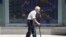 FILE - An elderly man walks by an electronic stock board of a securities firm in Tokyo, Aug. 19, 2016.