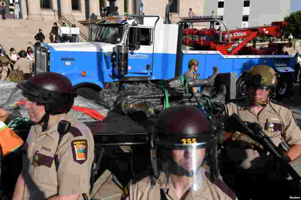 State Patrol officers stand guard as employees of Twin Cities Transport and Recovery work to clear the toppled statue of Christopher Columbus on the Minnesota State Capitol Grounds in St Paul, Minnesota, June 10, 2020.