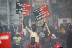 FILE - A protester holding placards rides on a motorbike during a march to demand an investigation into what they say is the alleged misuse of Venezuela-sponsored PetroCaribe funds, in Port-au-Prince, Haiti, Oct. 17, 2018.