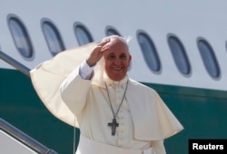 Pope Francis waves as he boards his plane to leave for his pastoral visit to South Korea, at the Fiumicino airport in Rome, Aug. 13, 2014.
