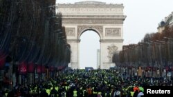 Protesters wearing yellow vests walk on the Champs-Elysees Avenue with the Arc de Triomphe in the background during a national day of protest by the "yellow vests" movement in Paris, Dec. 8, 2018.