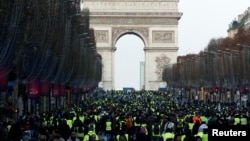 Protesters wearing yellow vests walk on the Champs-Elysees Avenue with the Arc de Triomphe in the background during a national day of protest by the "yellow vests" movement in Paris, Dec. 8, 2018.