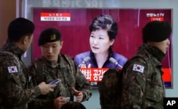 South Korean army soldiers pass by a TV screen showing the live broadcast of South Korean President Park Geun-hye's speech, at the Seoul Railway Station in Seoul, South Korea, Tuesday, Feb. 16, 2016.