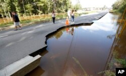 Pedestrians walk down Dorchester Road at Sawmill Branch Canal as it begins to wash away due to floodwaters near Summerville, S.C., Oct. 6, 2015. Residents are concerned that the Ashley river will continue to rise as floodwaters come down from Columbia.