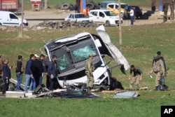 Members of Turkish forces gather around a bus that was destroyed in an explosion on the road linking the cities of Diyarbakir and Bingol, in southeastern Turkey, Feb. 18, 2016. Six soldiers were killed after PKK rebels detonated a bomb on the road.