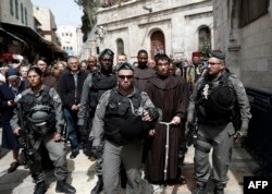 Israeli police forces escort Franciscan priests along the Via Dolorosa (Way of Suffering) in Jerusalem’s Old City during the Good Friday procession on March 25, 2016.