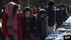 FILE - Visitors browse a book exhibition to mark International Women's Day at Kabul University, March 8, 2020. The Taliban say women have nothing to fear under their rule, but that's not how many educated Afghan women see it.