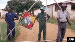 FILE - Police and black squatters guard the farm of an expelled white farmer in Mazowe, Zimbabwe, April 10, 2000.