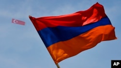 FILE - A Turkish flag attached to a small plane flies in the sky over an Armenian flag as protesters gather outside the Turkish Consulate to protest the deaths of an estimated 1.5 million Armenians under the Ottoman Empire, at a rally in Los Angeles, April 24, 2017.
