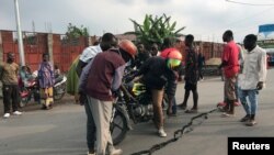 Les gens regardent une fissure sur la route causée par des tremblements de terre comme des répliques après l'éruption du volcan du mont Nyiragongo près de Goma, en République démocratique du Congo, le 26 mai 2021.