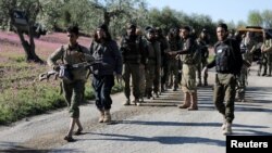 Turkish-backed Free Syrian Army fighters walk together after advancing north of Afrin, Syria, March 17, 2018. 