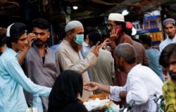 FILE - A man wearing a protective face mask gestures while shopping outside an electronics market, after Pakistan started easing lockdown restrictions, as the outbreak of the coronavirus disease continues, in Karachi, Pakistan, June 4, 2020.