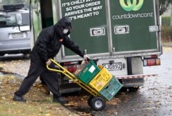 FILE - A delivery driver wearing a face mask delivers groceries to a home in central Christchurch, March 30, 2020.