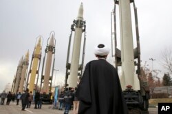 FILE - An Iranian clergyman looks at domestically built surface-to-surface missiles displayed by the Revolutionary Guard in a military show marking the 40th anniversary of the Islamic Revolution, at Imam Khomeini Grand Mosque in Tehran, Iran, Feb. 3, 2019.