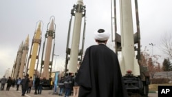 FILE - An Iranian clergyman looks at domestically built surface-to-surface missiles displayed by the Revolutionary Guard in a military show marking the 40th anniversary of the Islamic Revolution, at Imam Khomeini Grand Mosque in Tehran, Iran, Feb. 3, 2019