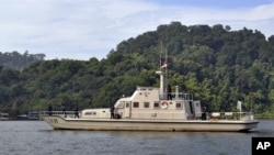 An Indonesian Navy boat carrying armed crew members patrol the waters near the prison island of Nusakambangan, background, where the planned executions of seven convicted foreign drug smugglers will be performed, in Cilacap, Central Java, Indonesia, Tuesd