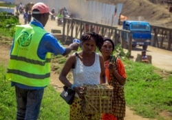 FILE - People crossing the border have their temperature taken to check for symptoms of Ebola, at the border crossing near Kasindi, eastern Congo, June 12, 2019, just across from the Ugandan town of Bwera.
