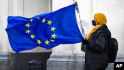 An anti-Brexit demonstrator holds an EU flag in Parliament Square, in London, Dec. 16, 2020.