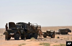 This photo, released Sept. 3, 2017, by the Syrian official news agency SANA, shows Syrian troops and pro-government gunmen standing near military vehicles on the outskirts of the eastern city of Deir el-Zour, Syria.