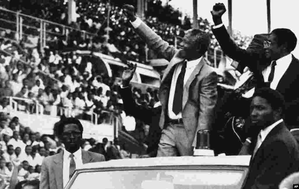 Deputy President of the African National Congress Nelson Mandela, center, and Zimbabwe President Robert Mugabe, far right, greet the crowds at the start of the new Zimbabwe public holiday, Mandela Day, March 5, 1990, in Harare.