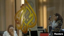 FILE - The Al Jazeera logo is seen through a window at the offices of the Arabic news channel in Ramallah, West Bank.