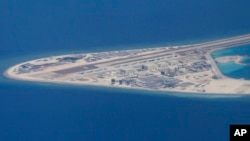 FILE - In this April 21, 2017, photo, an airstrip and buildings on China's man-made Subi Reef in the Spratly chain of islands in the South China Sea are seen from a Philippine Air Force C-130.