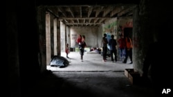 FILE - A migrant woman walks with her baby in a makeshift migrant camp in Bihac, 450 kms northwest of Sarajevo, Bosnia, Aug. 14, 2018. 