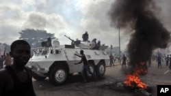 UN peacekeepers drive past supporters of Alassane Ouattara as they demonstrate and burn tires in the Abobo neighbourhood in Abidjan, February 19, 2011