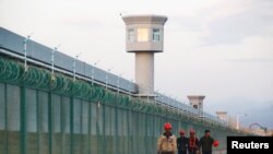 Workers walk by the perimeter fence of what is officially known as a vocational skills education center in Dabancheng in Xinjiang Uighur Autonomous Region, China, Sept. 4, 2018. 